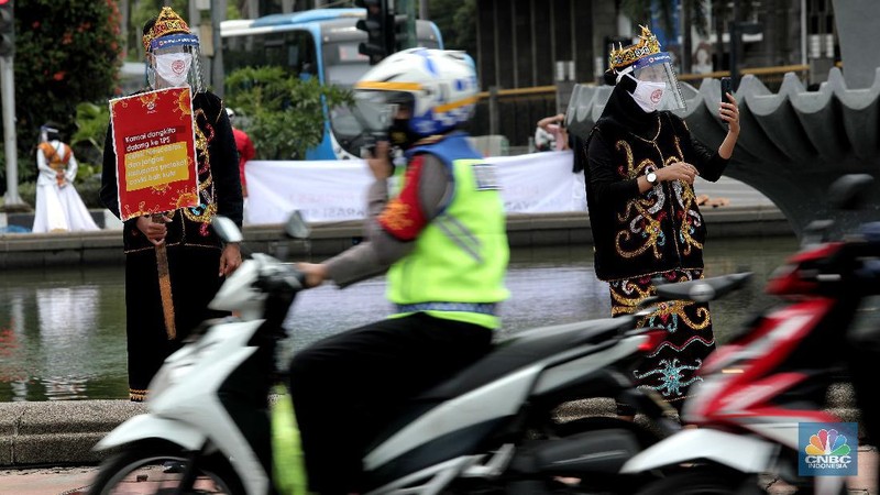 Aksi warga mengenakan pakaian adat menyerukan ajakan patuhi aturan Covid-19 saat Pilkada berlangsung disejumlah daerah di Kawasan Patung Kuda Monas, Jakarta, Senin 7/12. (CNBC Indonesia/Muhammad Sabki)