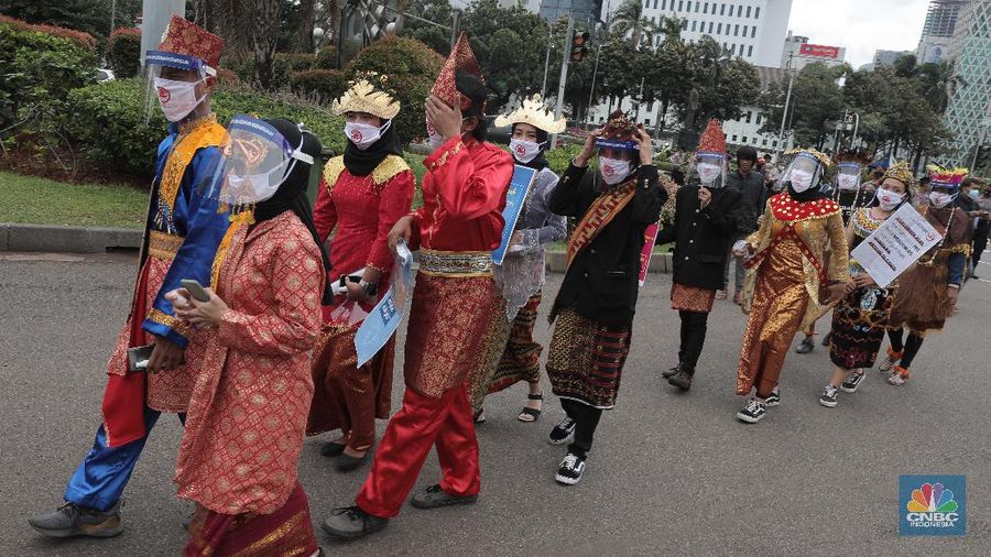 Aksi warga mengenakan pakaian adat menyerukan ajakan patuhi aturan Covid-19 saat Pilkada berlangsung disejumlah daerah di Kawasan Patung Kuda Monas, Jakarta, Senin 7/12. (CNBC Indonesia/Muhammad Sabki)