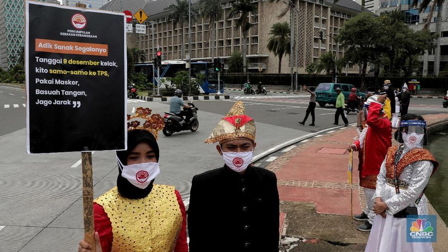 Aksi warga mengenakan pakaian adat menyerukan ajakan patuhi aturan Covid-19 saat Pilkada berlangsung disejumlah daerah di Kawasan Patung Kuda Monas, Jakarta, Senin 7/12. (CNBC Indonesia/Muhammad Sabki)