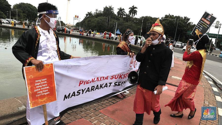 Aksi warga mengenakan pakaian adat menyerukan ajakan patuhi aturan Covid-19 saat Pilkada berlangsung disejumlah daerah di Kawasan Patung Kuda Monas, Jakarta, Senin 7/12. (CNBC Indonesia/Muhammad Sabki)