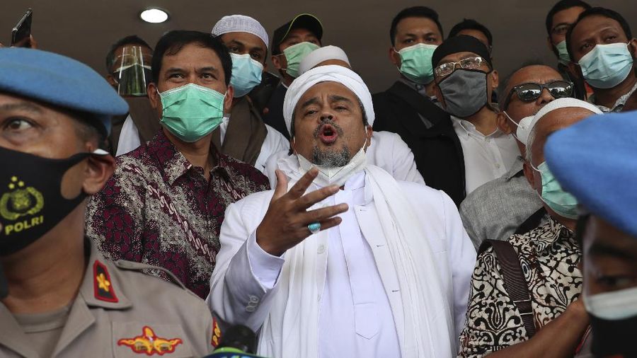 Indonesian Islamic cleric and the leader of Islamic Defenders Front Rizieq Shihab, center, talks to reporters upon arrival at the regional police headquarters in Jakarta, Indonesia. Saturday, Dec. 12, 2020. The firebrand cleric turned himself in to the police after he was accused of inciting people to breach pandemic restrictions by holding events with large crowds. Shihab arrived at Jakarta police headquarters a day after police warned they would arrest him after he ignored several summonses. (AP Photo/Achmad Ibrahim)