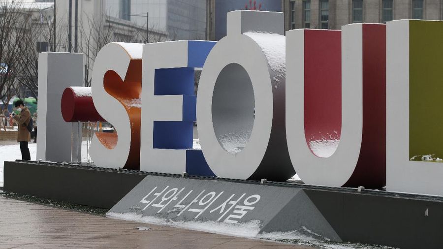 A man wearing a face mask as a precaution against the coronavirus, stands near the display of South Korea's capital Seoul logo in downtown Seoul, South Korea, Sunday, Dec. 13, 2020. (AP Photo/Lee Jin-man)