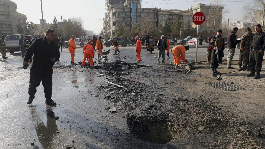 Afghan municipality workers clean the remains of a vehicle after a bomb blast in Kabul, Afghanistan, Sunday, Dec. 13, 2020. A sticky bomb attached to an armored vehicle in northern Kabul killed a few, and wounded at least a few others, according to Ferdaws Faramarz, a spokesman for the Kabul police chief. No further details were immediately available.(AP Photo/Rahmat Gul)