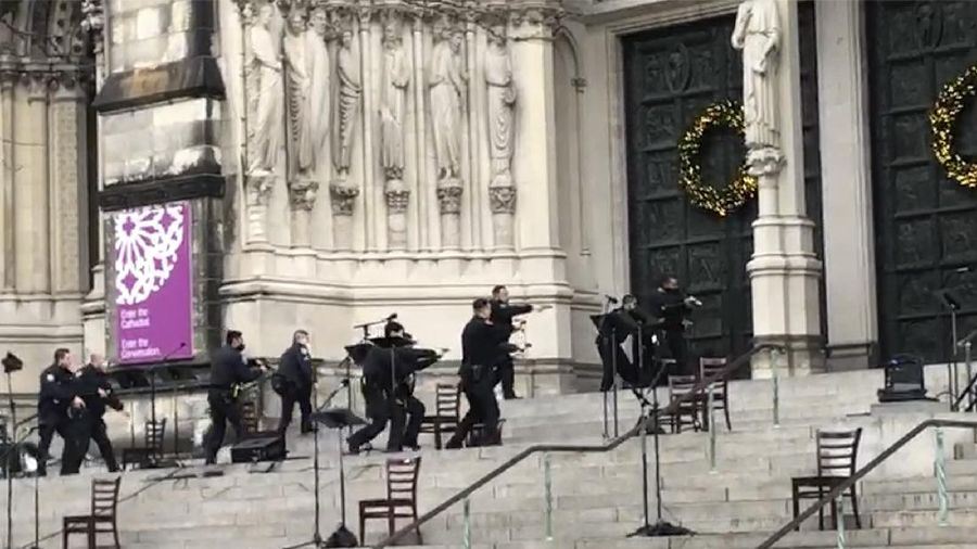 Emergency medical personnel pull a stretcher up to the scene of a shooting at the Cathedral Church of St. John the Divine, Sunday, Dec. 13, 2020, in New York. A man was shot by police after shots rang out at the end of a Christmas choral concert on the steps of the Manhattan cathedral Sunday afternoon. The shooting happened just before 4 p.m. at the church which is the mother church of the Episcopal Diocese of New York and seat of its bishop. (AP Photo/Ted Shaffrey)