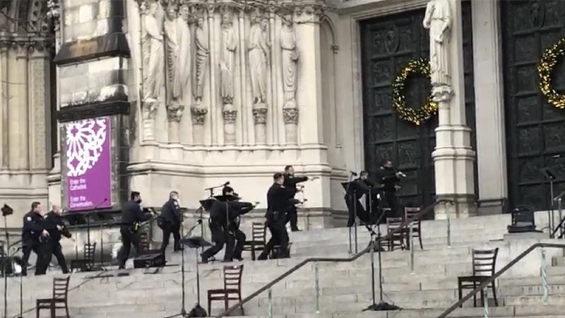 Emergency medical personnel pull a stretcher up to the scene of a shooting at the Cathedral Church of St. John the Divine, Sunday, Dec. 13, 2020, in New York. A man was shot by police after shots rang out at the end of a Christmas choral concert on the steps of the Manhattan cathedral Sunday afternoon. The shooting happened just before 4 p.m. at the church which is the mother church of the Episcopal Diocese of New York and seat of its bishop. (AP Photo/Ted Shaffrey)