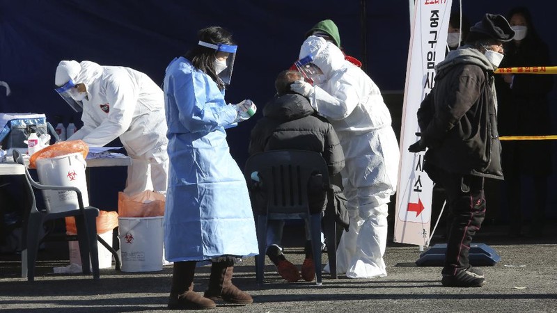 A medical worker takes samples from a man during a COVID-19 testing at a makeshift clinic in Seoul, South Korea, Monday, Dec. 14, 2020. South Korea was opening dozens of free COVID-19 testing sites in the greater Seoul area, as the country registered additional more than 700 new cases Monday amid a surge in infections. (AP Photo/Ahn Young-joon)