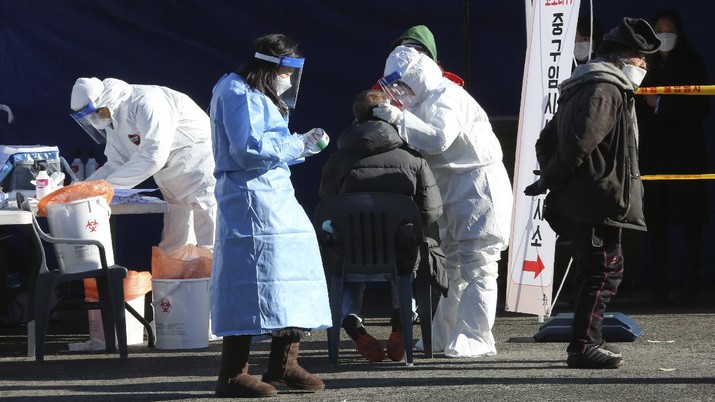 Wabah Covid-19 di Korea Selatan A medical worker takes samples from a man during a COVID-19 testing at a makeshift clinic in Seoul, South Korea, Monday, Dec. 14, 2020. South Korea was opening dozens of free COVID-19 testing sites in the greater Seoul area, as the country registered additional more than 700 new cases Monday amid a surge in infections. (AP Photo/Ahn Young-joon)