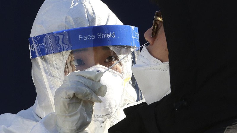 A medical worker takes samples from a man during a COVID-19 testing at a makeshift clinic in Seoul, South Korea, Monday, Dec. 14, 2020. South Korea was opening dozens of free COVID-19 testing sites in the greater Seoul area, as the country registered additional more than 700 new cases Monday amid a surge in infections. (AP Photo/Ahn Young-joon)