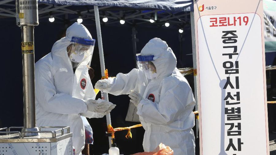 A medical worker takes samples from a man during a COVID-19 testing at a makeshift clinic in Seoul, South Korea, Monday, Dec. 14, 2020. South Korea was opening dozens of free COVID-19 testing sites in the greater Seoul area, as the country registered additional more than 700 new cases Monday amid a surge in infections. (AP Photo/Ahn Young-joon)