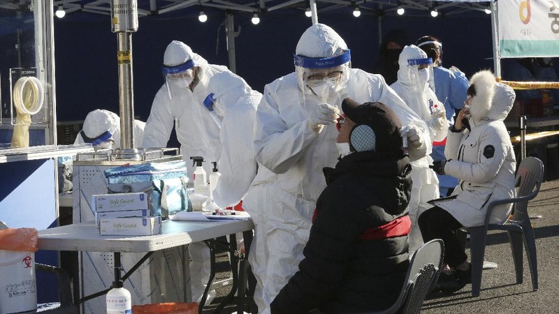A medical worker takes samples from a man during a COVID-19 testing at a makeshift clinic in Seoul, South Korea, Monday, Dec. 14, 2020. South Korea was opening dozens of free COVID-19 testing sites in the greater Seoul area, as the country registered additional more than 700 new cases Monday amid a surge in infections. (AP Photo/Ahn Young-joon)
