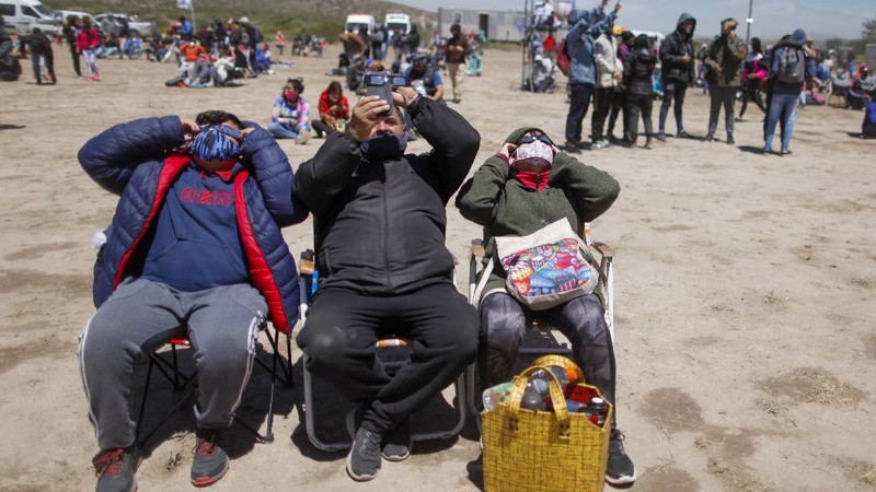 People walk on a dune, a day before a total eclipse in Nahuelpan, La Araucania, Chile,Sunday, Dec. 13, 2020. The total eclipse will be visible from Chile and the northern Patagonia region of Argentina, and as a partial solar eclipse in Bolivia, Brazil, Ecuador, Paraguay, Peru and Uruguay. (AP Photo/Esteban Felix)