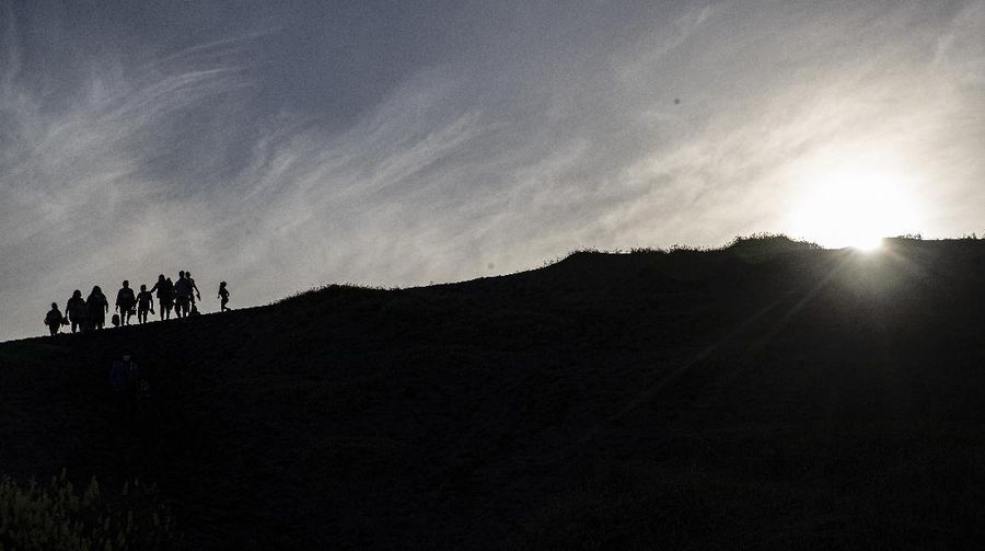 People walk on a dune, a day before a total eclipse in Nahuelpan, La Araucania, Chile,Sunday, Dec. 13, 2020. The total eclipse will be visible from Chile and the northern Patagonia region of Argentina, and as a partial solar eclipse in Bolivia, Brazil, Ecuador, Paraguay, Peru and Uruguay. (AP Photo/Esteban Felix)