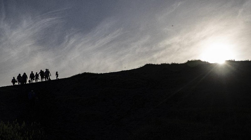 People walk on a dune, a day before a total eclipse in Nahuelpan, La Araucania, Chile,Sunday, Dec. 13, 2020. The total eclipse will be visible from Chile and the northern Patagonia region of Argentina, and as a partial solar eclipse in Bolivia, Brazil, Ecuador, Paraguay, Peru and Uruguay. (AP Photo/Esteban Felix)