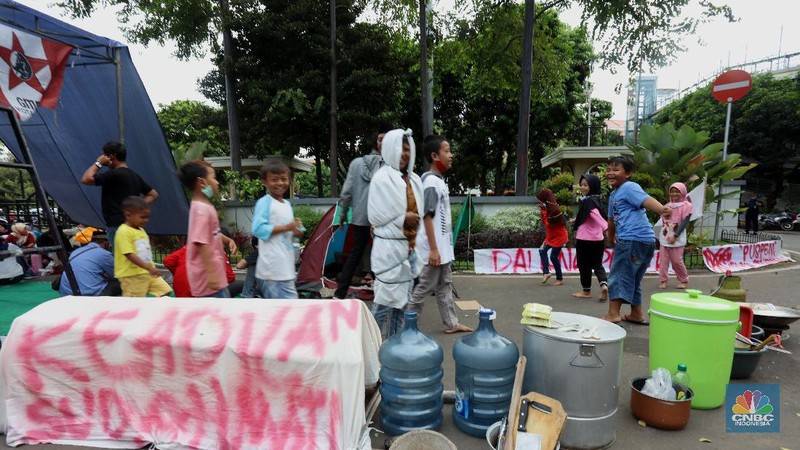 Sejumlah warga terdampak pembangunan Tol JORR II  melakukan aksi dengan mendirikan tenda dan dapur di halaman Gedung Pemerintahan Kota Tangerang, Banten, Selasa (15/12/2020). Aksi tersebut menuntut pemerintahan daerah ikut andil terkait permasalahan uang kompensasi akibat penggusuran untuk proyek pembangunan jalan Tpl JORR II yang dianggap tidak sesuai dengan harapan warga.  (CNBC Indonesia/Tri Susilo)