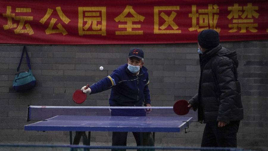 People wearing face masks to help curb the spread of the coronavirus walk across a street as they head for work during the morning rush hour in Beijing, Tuesday, Dec. 15, 2020. (AP Photo/Andy Wong)