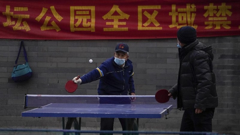 People wearing face masks to help curb the spread of the coronavirus walk across a street as they head for work during the morning rush hour in Beijing, Tuesday, Dec. 15, 2020. (AP Photo/Andy Wong)