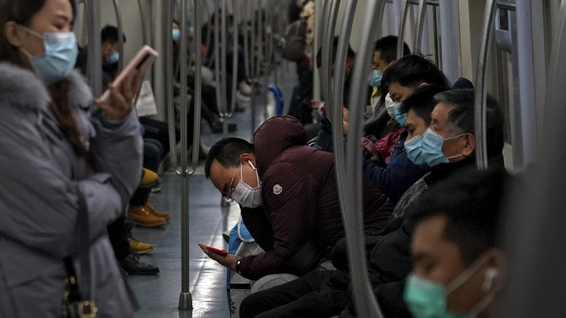 People wearing face masks to help curb the spread of the coronavirus walk across a street as they head for work during the morning rush hour in Beijing, Tuesday, Dec. 15, 2020. (AP Photo/Andy Wong)
