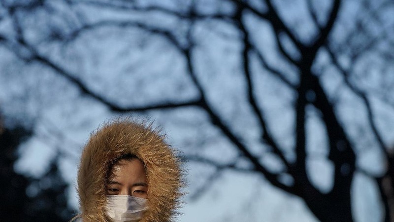 People wearing face masks to help curb the spread of the coronavirus walk across a street as they head for work during the morning rush hour in Beijing, Tuesday, Dec. 15, 2020. (AP Photo/Andy Wong)