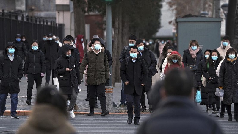 People wearing face masks to help curb the spread of the coronavirus walk across a street as they head for work during the morning rush hour in Beijing, Tuesday, Dec. 15, 2020. (AP Photo/Andy Wong)