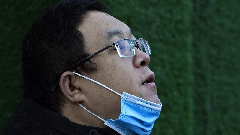 People wearing face masks to help curb the spread of the coronavirus walk across a street as they head for work during the morning rush hour in Beijing, Tuesday, Dec. 15, 2020. (AP Photo/Andy Wong)