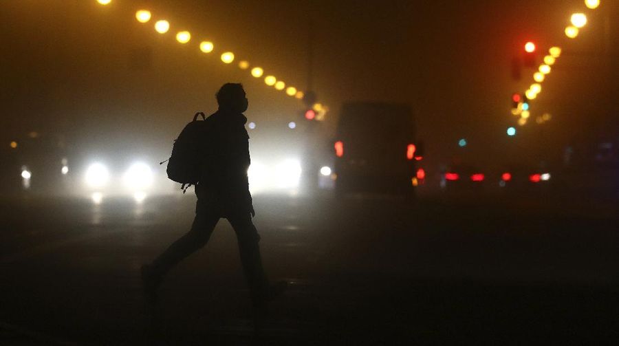 A man wears a face mask as he crosses a road early morning in Munich, Germany, Wednesday, Dec. 16, 2020. Germany has entered a harder lockdown, closing shops and schools in an effort to bring down stubbornly high new cases of the coronavirus. (AP Photo/Matthias Schrader)