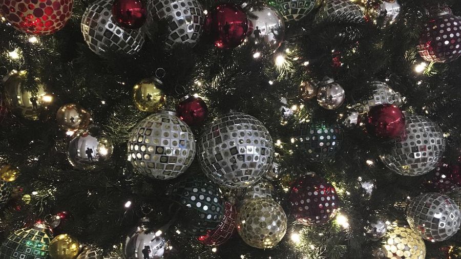 FILE - In this Friday, Dec. 1, 2017, file photo, ornaments hang on a Christmas tree on display in New York. Office holiday parties are tricky in 2020 amid the coronavirus pandemic. Dancing, drinking and fancy dinners are out. Many companies are foregoing parties altogether, deciding instead to send staff gift baskets, extra time off or donations to charities that employees choose. (AP Photo/Swayne B. Hall, File)