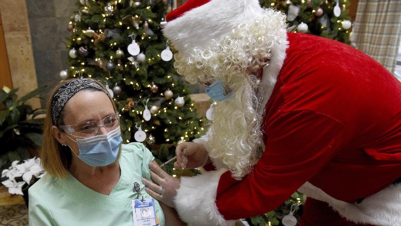 Santa, Robert Carroll, M.D., an Emergency Medicine Specialist with Manchester Memorial Hospital, administers the Pfizer-BioNTech vaccine to R.N. Diana Flebeau, a front-line healthcare worker, Wednesday, Dec. 16, 2020, in Manchester, Conn.   (Jim Michaud/Journal Inquirer via AP)