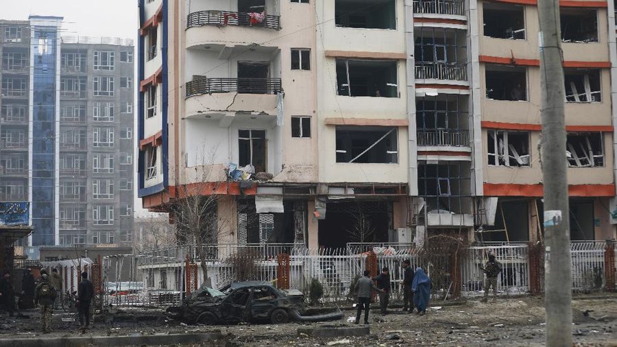 An Afghan man looks through a glass window damaged after a bombing attack in Kabul, Afghanistan, Sunday, Dec. 20, 2020. The strong car bomb explosion rocked the capital Kabul city on Sunday morning, killing multiple people, said a government official. (AP Photo/Rahmat Gul)