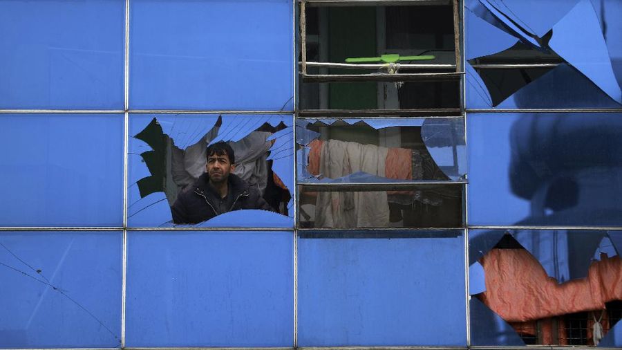 An Afghan man looks through a glass window damaged after a bombing attack in Kabul, Afghanistan, Sunday, Dec. 20, 2020. The strong car bomb explosion rocked the capital Kabul city on Sunday morning, killing multiple people, said a government official. (AP Photo/Rahmat Gul)