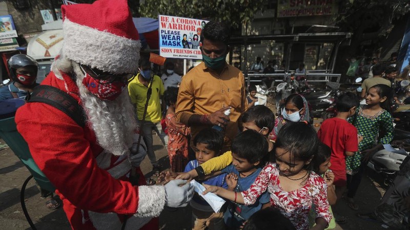 A man dressed as Santa Claus sanitizes an autorickshaw in Dharavi, one of Asia's biggest slums, in Mumbai, India, Saturday, Dec. 19, 2020. India's coronavirus cases have crossed 10 million with new infections dipping to their lowest levels in three months, as the country prepares for a massive COVID-19 vaccination in the new year. (AP Photo/Rafiq Maqbool)