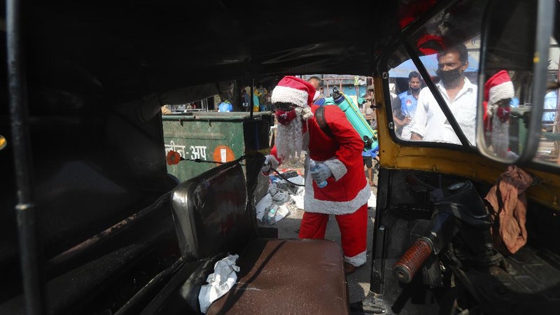 A man dressed as Santa Claus sanitizes an autorickshaw in Dharavi, one of Asia's biggest slums, in Mumbai, India, Saturday, Dec. 19, 2020. India's coronavirus cases have crossed 10 million with new infections dipping to their lowest levels in three months, as the country prepares for a massive COVID-19 vaccination in the new year. (AP Photo/Rafiq Maqbool)