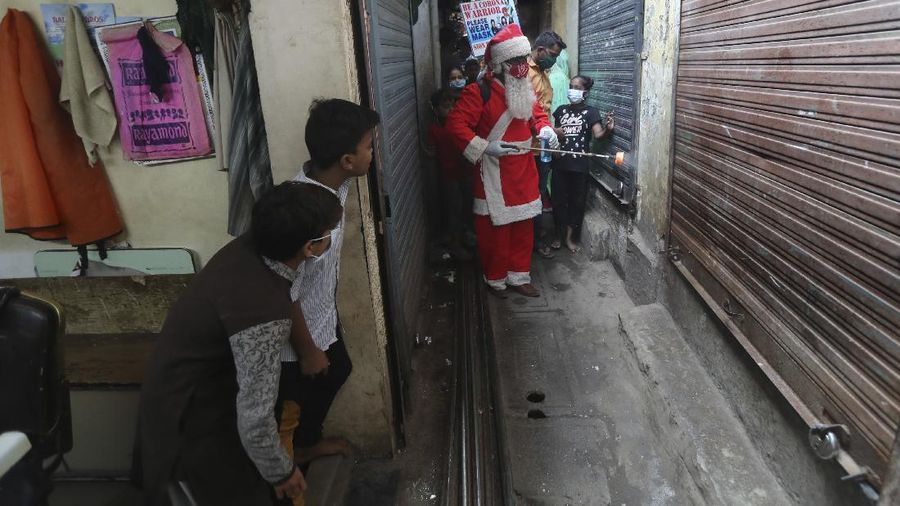 A man dressed as Santa Claus sanitizes an autorickshaw in Dharavi, one of Asia's biggest slums, in Mumbai, India, Saturday, Dec. 19, 2020. India's coronavirus cases have crossed 10 million with new infections dipping to their lowest levels in three months, as the country prepares for a massive COVID-19 vaccination in the new year. (AP Photo/Rafiq Maqbool)