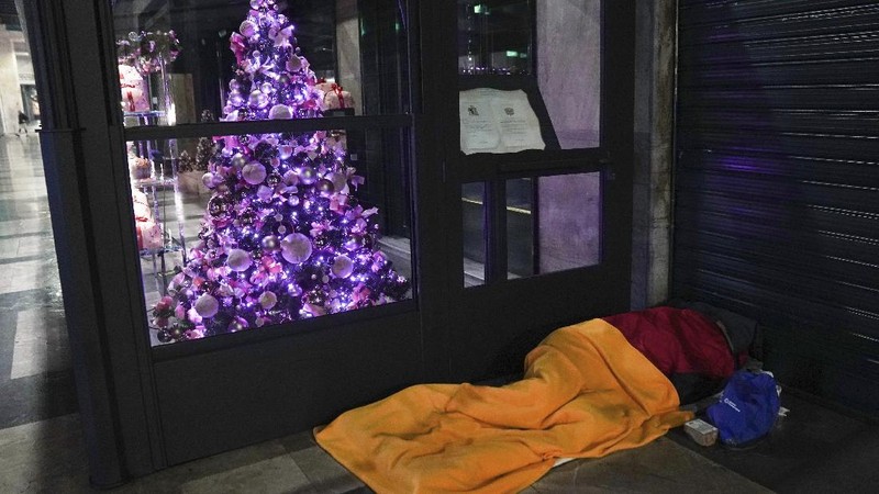 A homeless sleeps on the floor in front of a fashion store in downtown Milan, northern Italy, Friday, Nov. 27, 2020. Nowhere in Italy is poverty more evident than in Lombardy, the northern region that has been the pandemic epicenter in both surges. The Coldiretti agriculture lobby estimates that the virus has created 300,000 so-called 