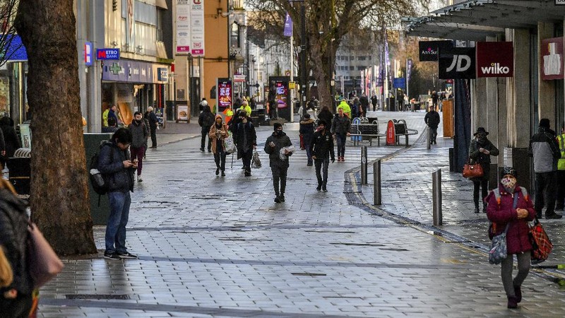 People walk through Cardiff city centre, Sunday Dec. 20, 2020. In Wales, authorities said they decided to move up a lockdown planned for after Christmas and people must stay at home from 12:01 a.m. Sunday. The move will largely scrap Christmas gatherings in line with the rules for southern England. (Ben Birchall/PA via AP)