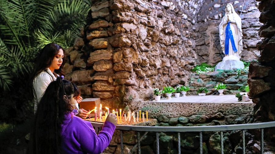 Worshippers sit spaced apart to prevent the spread of coronavirus outbreak as they light candles during a Christmas Eve service at Immanuel Church in Jakarta, Indonesia, Thursday, Dec. 24, 2020. Christmas celebrations in Indonesia will be a low-key affair amid surging coronavirus cases in the world's fourth most populous nation. (AP Photo/Dita Alangkara)