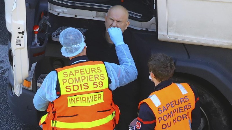 French officers make a COVID-19 test to a truck driver in the Port of Dover in Dover, England, Thursday, Dec. 24, 2020. Freight from Britain and passengers with a negative virus test have begun arriving on French shores, after France relaxed a two-day blockade over a new virus variant. The blockade had isolated Britain, stranded thousands of drivers and raised fears of shortages. (AP Photo/Alberto Pezzali)