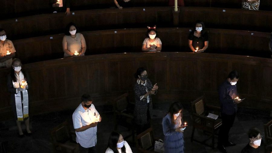 Worshippers sit spaced apart to prevent the spread of coronavirus outbreak as they light candles during a Christmas Eve service at Immanuel Church in Jakarta, Indonesia, Thursday, Dec. 24, 2020. Christmas celebrations in Indonesia will be a low-key affair amid surging coronavirus cases in the world's fourth most populous nation. (AP Photo/Dita Alangkara)