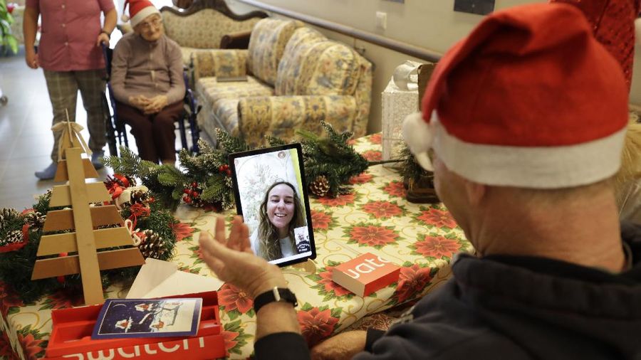 Roberto Capellini, is flanked by carer Michela Valle, right, and director Maria Giulia Madaschi, as he talks on  video call with Carolina Giannesi, a donor unrelated to her, who bought and sent her a Christmas present through an organization dubbed 