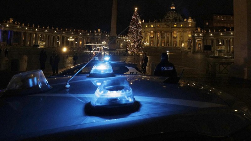 Police watch over as faithful pray outside St. Peter's Square, at the Vatican, Thursday, Dec. 24, 2020. Police in Italy are enforcing new COVID-19 travel restrictions aimed at limiting far-flung families from gathering over Christmas. Public health officials appealed for people to use common sense to prevent new infections over the holidays as a modified nationwide lockdown took effect Thursday. (AP Photo/Gregorio Borgia)