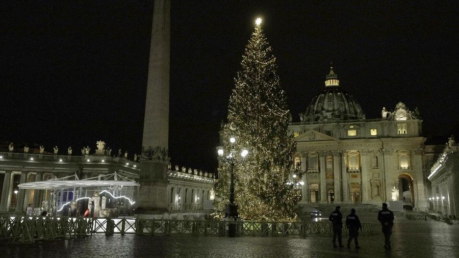 Police watch over as faithful pray outside St. Peter's Square, at the Vatican, Thursday, Dec. 24, 2020. Police in Italy are enforcing new COVID-19 travel restrictions aimed at limiting far-flung families from gathering over Christmas. Public health officials appealed for people to use common sense to prevent new infections over the holidays as a modified nationwide lockdown took effect Thursday. (AP Photo/Gregorio Borgia)