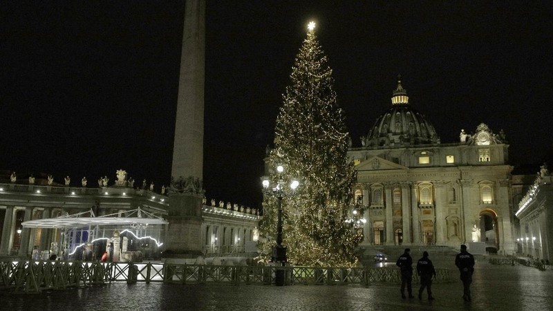 Police watch over as faithful pray outside St. Peter's Square, at the Vatican, Thursday, Dec. 24, 2020. Police in Italy are enforcing new COVID-19 travel restrictions aimed at limiting far-flung families from gathering over Christmas. Public health officials appealed for people to use common sense to prevent new infections over the holidays as a modified nationwide lockdown took effect Thursday. (AP Photo/Gregorio Borgia)