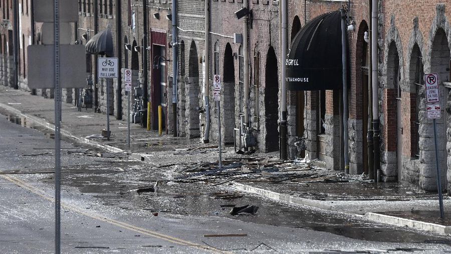A law enforcement member walks past damage from an explosion in downtown Nashville, Tenn., Friday, Dec. 25, 2020. Buildings shook in the immediate area and beyond after a loud boom was heard early Christmas morning. (AP Photo/Mark Humphrey)