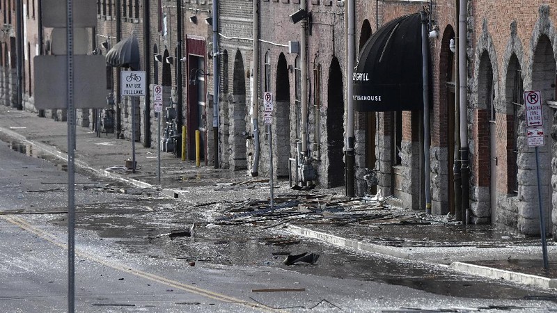 A law enforcement member walks past damage from an explosion in downtown Nashville, Tenn., Friday, Dec. 25, 2020. Buildings shook in the immediate area and beyond after a loud boom was heard early Christmas morning. (AP Photo/Mark Humphrey)