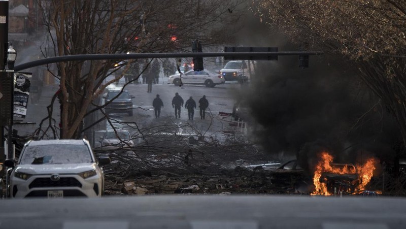 A law enforcement member walks past damage from an explosion in downtown Nashville, Tenn., Friday, Dec. 25, 2020. Buildings shook in the immediate area and beyond after a loud boom was heard early Christmas morning. (AP Photo/Mark Humphrey)