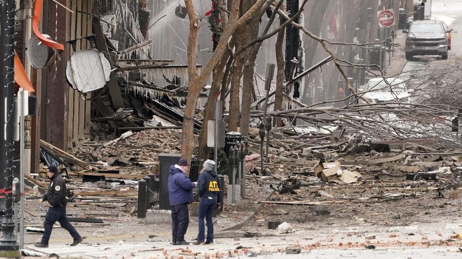 A law enforcement member walks past damage from an explosion in downtown Nashville, Tenn., Friday, Dec. 25, 2020. Buildings shook in the immediate area and beyond after a loud boom was heard early Christmas morning. (AP Photo/Mark Humphrey)