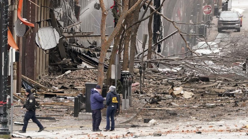 A law enforcement member walks past damage from an explosion in downtown Nashville, Tenn., Friday, Dec. 25, 2020. Buildings shook in the immediate area and beyond after a loud boom was heard early Christmas morning. (AP Photo/Mark Humphrey)