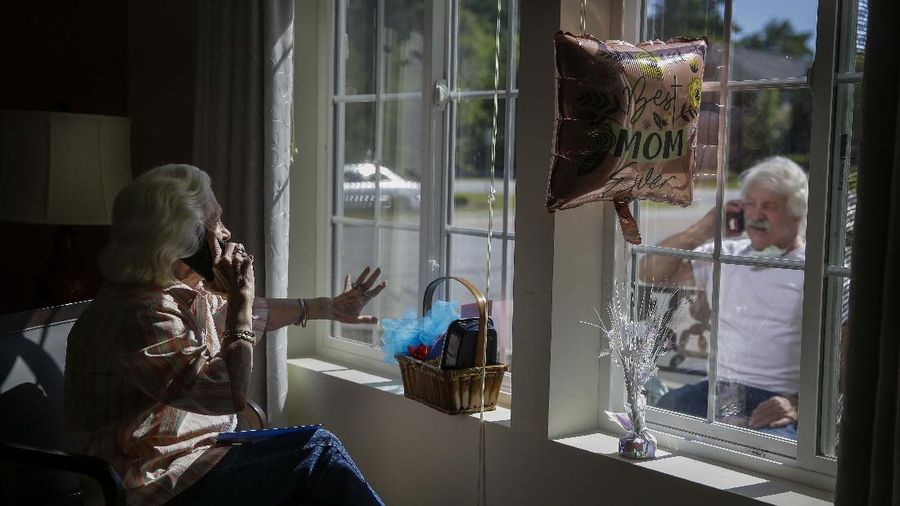 Foto terbaik AP 2020, Mary Faye Cochran, 86, menyanyikan "You Are My Sunshine" melalui telepon kepada putranya Stacey Smith melalui jendela pada Hari Ibu. (AP/Brynn Anderson)