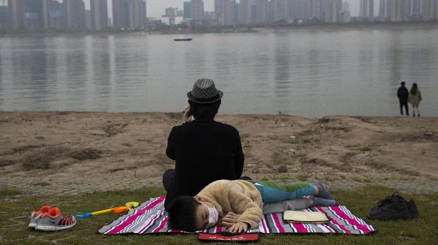 Foto terbaik AP 2020, Seorang anak yang mengenakan masker untuk melindungi diri dari virus korona berada di tepi Sungai Yangtze di Wuhan di provinsi Hubei China tengah pada. (AP/Ng Han Guan)
