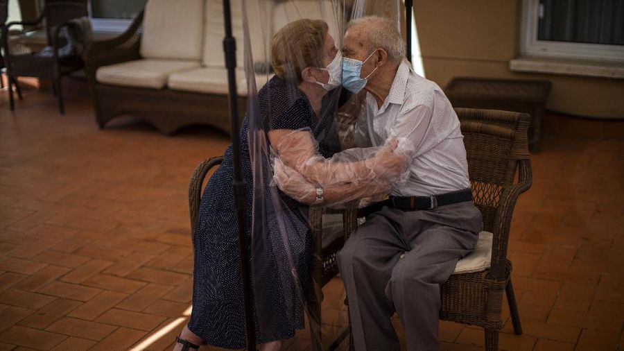 Agustina Cañamero (81) dan Pascual Pérez (84) berpelukan dan berciuman dengan dihalangi plastik untuk menghindari tertular virus corona di panti jompo di Barcelona, Spanyol, Senin, 22 Juni 2020. (AP / Emilio Morenatti)
