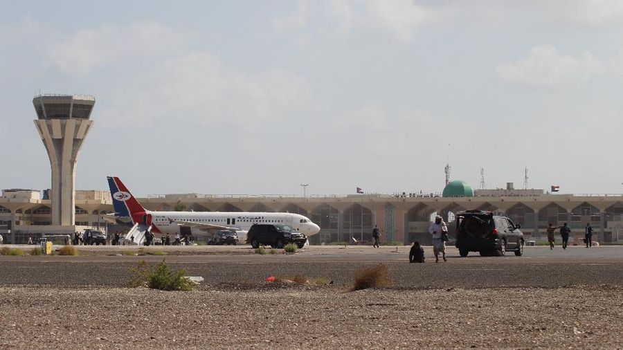 Bystanders stand near the runway of Yemen southern city of Aden’s airport shortly after an explosion hit as a government plane landed, Wednesday, Dec. 30, 2020. The blast struck the airport building shortly after a Yemenia airlines plane carrying the newly formed Cabinet landed. No one on the government plane was hurt.  (AP Photo/Wael Qubady)